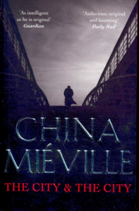 The cover of 'The City and the City' by China Miéville. It shows the silhouette of a man against a bleak cloudy sky, standing at the top of a ramp.